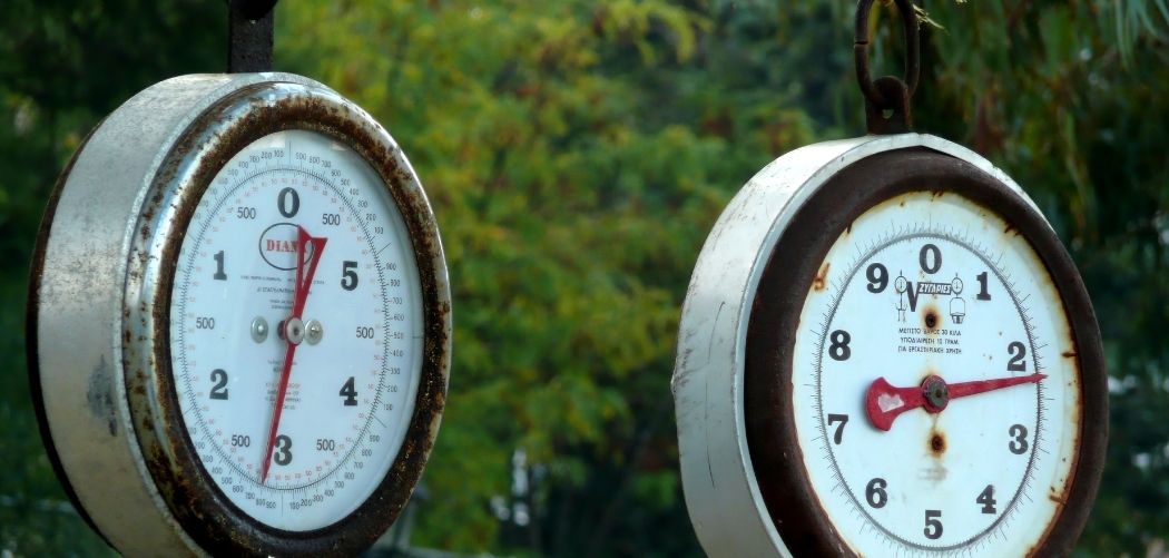 Two large dial scales hanging outdoors with the needle faces showing